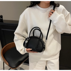 Détail du sac à main noir grainé avec breloque cœur argentée et bandoulière fine