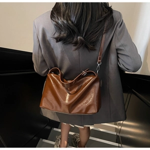 Brown polished leather crossbody pillow bag shown on model for stylish size perspective