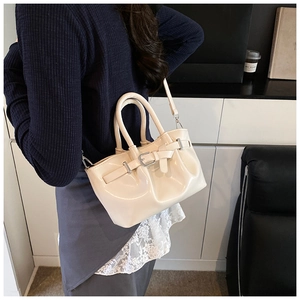 Close-up of beige glossy bucket bag with silver buckle and adjustable shoulder strap