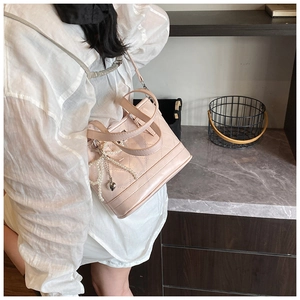 Close-up of pink quilted leather handbag with pearl bow and silver heart pendant