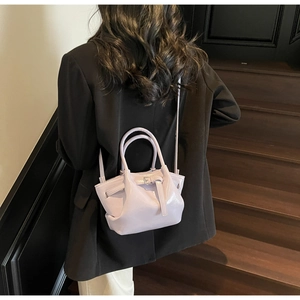 Sac seau moderne violet clair brillant porté sur un blazer noir par un mannequin élégant