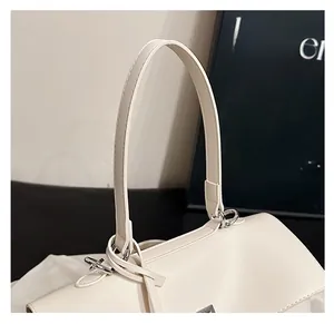 Detail of white leather tote bag featuring slim shoulder straps and silver metal hardware