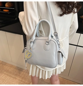 Detail of light blue Boston tote bag with a yellow heart pendant in a kitchen setting