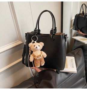 Detail of black lychee texture bucket bag with cute bear charm and metal buckle