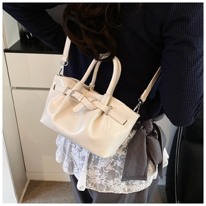 Detail of off-white glossy patent leather bucket bag with stylish pleats and strap