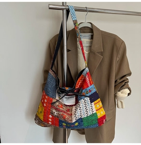 Detail of a large patchwork denim tote bag with ethnic prints and bow on a metal hanger