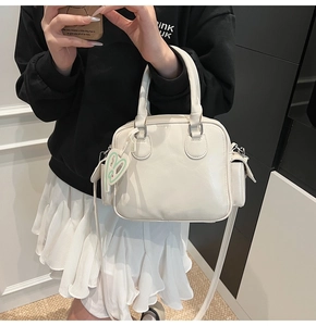 Detail of off-white Boston tote bag with heart charm and leather texture on a shoulder strap