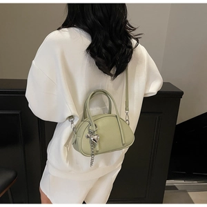 Détail du sac polochon vert sauge avec texture en cuir grainé et pendentif en cœur