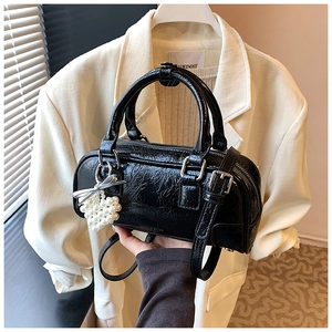 Détail du sac bowling en cuir verni noir avec un pendentif cœur en perles et finitions argentées