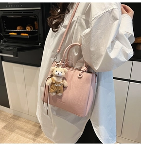 Pink lychee texture bucket bag detail with cute teddy bear charm on model shoulder