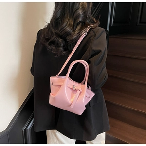 Détail d'un sac seau rose en cuir verni avec boucle latérale et fini brillant chic