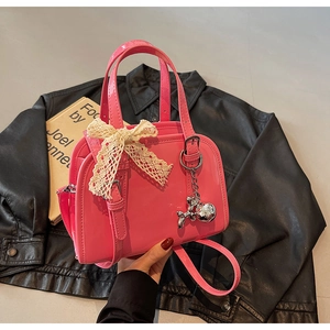 Detail of bright pink patent leather Boston bag with lace bow and silver balloon dog charm