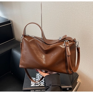 Detail of dark brown glossy leather pillow bag with silver zipper and double straps