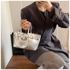 Detail of silver metallic tote bag featuring dual handles and polished buckles on leather