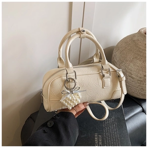 Close-up of cream white bowling bag with pearl grape charm and bow detail