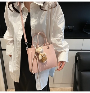Pink lychee grain leather bucket bag with cute bear pendant in a modern lifestyle setting