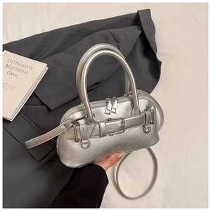 Detail of silver shell bag with metallic finish, double zippers, and buckle detail