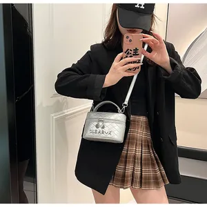 Détail du sac boîte argenté matelassé avec bandoulière chaîne et poignée porté par mannequin