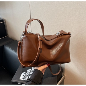 Detail of dark brown glossy faux leather handbag with silver metallic twist lock closure