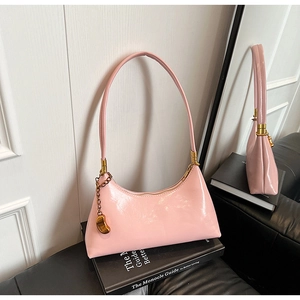 Detail der glänzenden rosa Lackleder-Hobo-Tasche mit Goldbeschlägen und Anhänger
