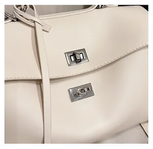 Detail of silver twist-lock hardware on a creamy white soft leather tote bag