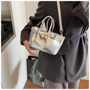 Silver metallic bucket bag with pleated texture and adjustable shoulder strap worn by model
