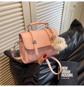Detail of pink faux leather handbag with silver studs and a cute plush monster charm