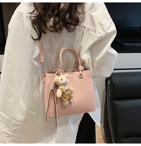 Pink lychee grain leather bucket bag with top handles and a cute plush bear charm
