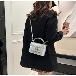 Sac boîte argenté matelassé avec texture métallique et lettrage de marque élégant