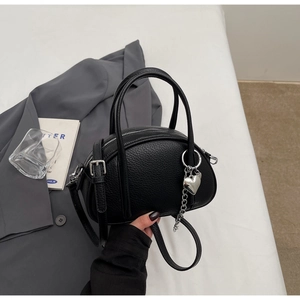 Détail du mini sac à main en cuir noir avec breloque cœur argentée et chaîne métal