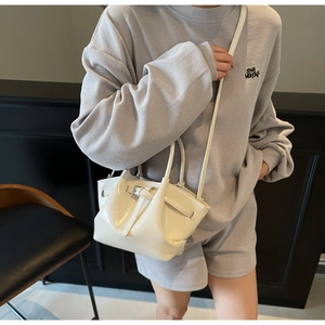 Détail du sac seau plissé blanc crème avec boucle argentée sur un ensemble gris sport
