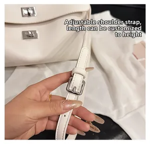Detail view of the adjustable leather shoulder strap with silver buckle on a beige tote bag