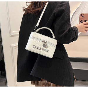 Détail du sac bandoulière matelassé blanc avec logo métallique et pendentif en cœur