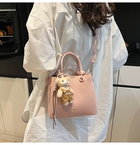 Pink lychee grain leather bucket bag with top handles and a cute teddy bear pendant