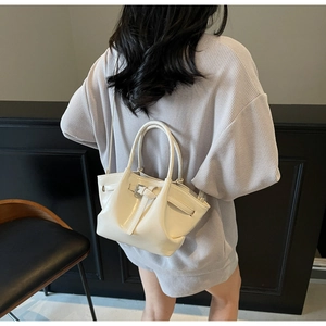 Détail d'un sac seau minimaliste en similicuir blanc crème avec finition brillante et anses