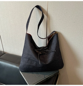 Detail of grey denim tote bag with Romance lettering and red patterned lining on leather sofa