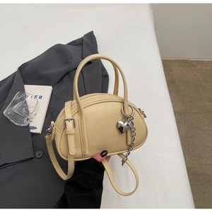 Détail d'un sac à main en cuir grainé avec pendentif coeur et bandoulière réglable