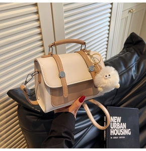 Detail of two-tone crossbody bag with plush charm and silver metallic accents