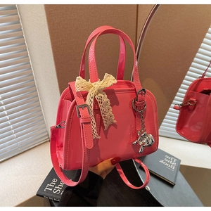 Detail of pink patent leather Boston bag with lace bow and silver bear charm