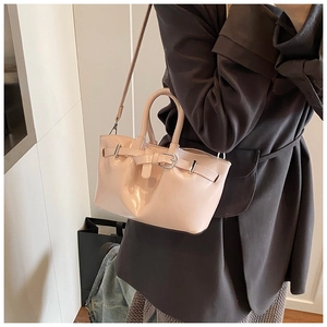 Side view of pink patent leather bucket bag with silver buckle and detachable shoulder strap