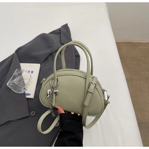 Détail du cuir vert clair à texture litchi et du pendentif coeur argenté du sac