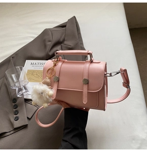 Pink PU leather square handbag detail with circular metal buckle and plush charm
