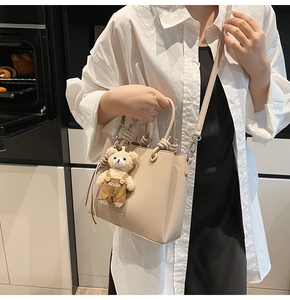 Detail of apricot bucket bag with lychee texture and cute teddy bear charm