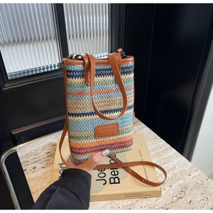Close-up of a colorful striped woven phone bag with brown leather handles and brand tag