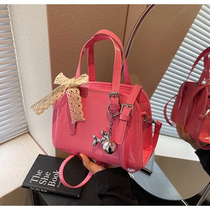 Detail of glossy pink patent leather Boston bag with lace bow and silver dog charm
