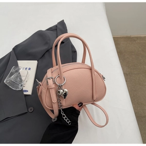 Détail du sac boston en cuir rose avec breloque cœur argentée et bandoulière réglable