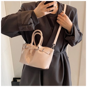 Detail shot of glossy patent leather handbag with decorative buckle and slim strap
