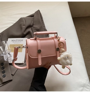 Pink leather handbag with metal buckle detail and white plush pompom charm