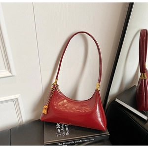 Detail einer roten glänzenden Hobo-Tasche mit goldenen Beschlägen und Reißverschluss