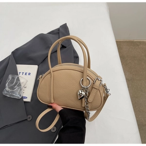 Détail du sac à main beige en cuir grainé avec pendentif cœur et chaîne argent